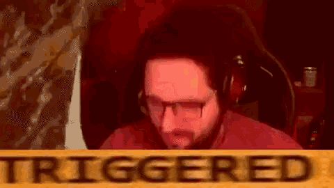 a man wearing glasses and headphones is sitting in a chair in front of a sign that says triggered .