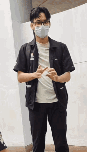 a man wearing a mask and glasses stands in front of a wall