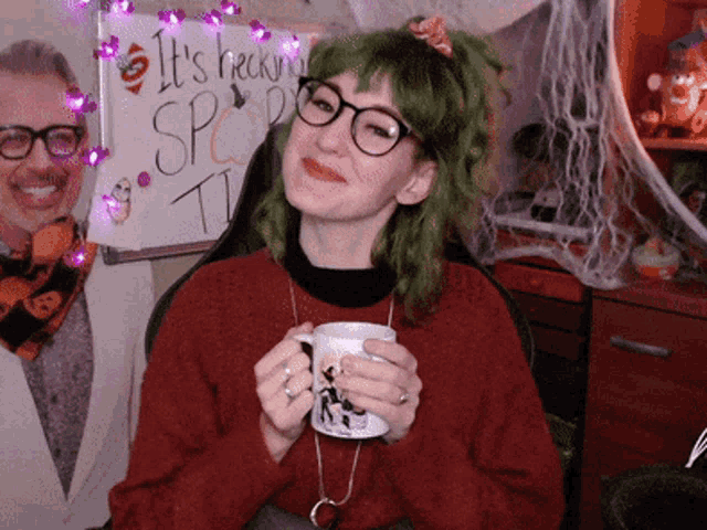 a woman with green hair is holding a cup in front of a sign that says it 's trick or treat time