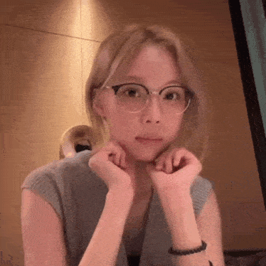a young woman wearing glasses and a bracelet is making a funny face .