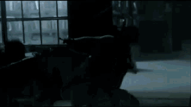 a group of people are standing in a dark room with a window .