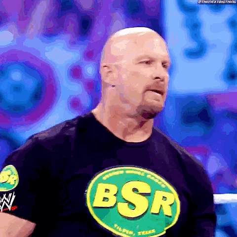 a bald man wearing a bsr t-shirt stands in a ring
