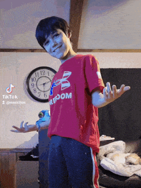 a young boy wearing a red shirt that says freedom stands in front of a clock