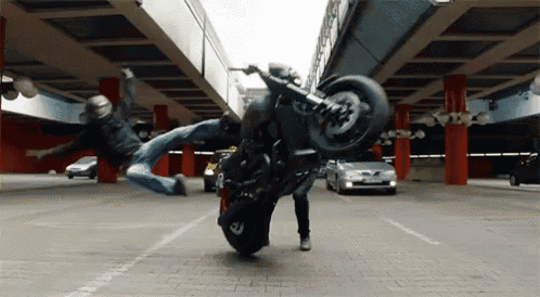 a man on a motorcycle is doing a trick in a parking lot