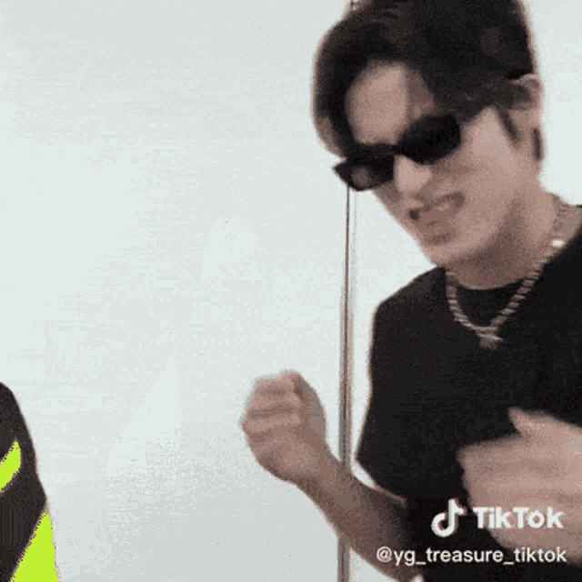 a young man wearing sunglasses and a necklace is making a funny face .