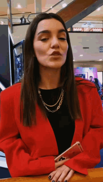a woman wearing a red jacket is holding a phone