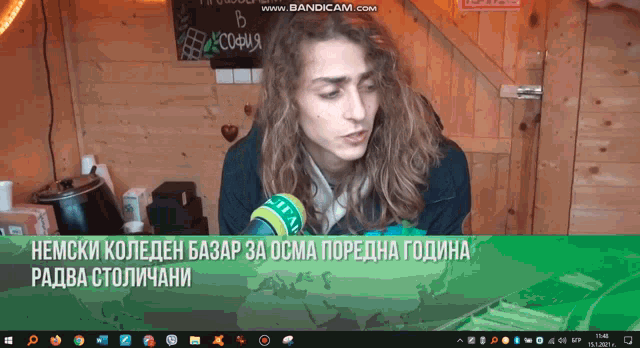 a man with long hair is talking into a microphone in front of a computer screen that says bandicam.com