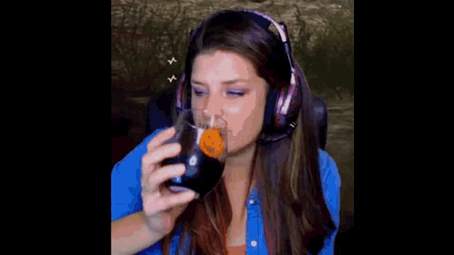 a woman wearing headphones is drinking from a glass .