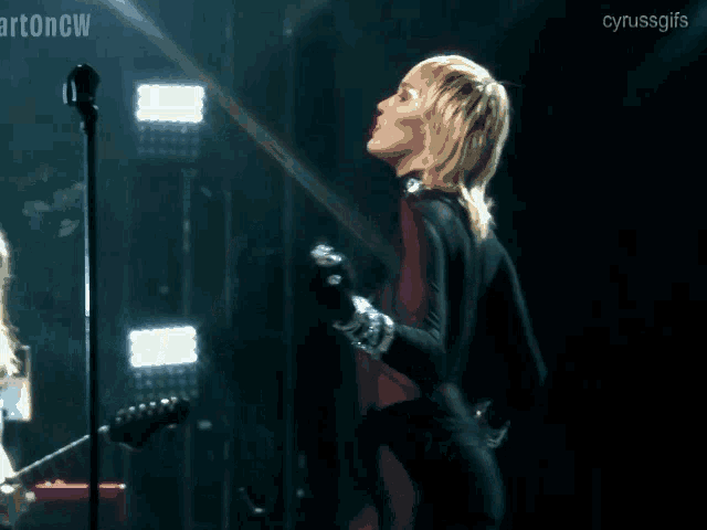 a woman singing into a microphone with the words cyrussgifs written on the bottom