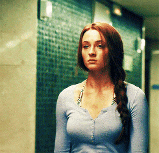 a woman with braided hair is wearing a blue sweater