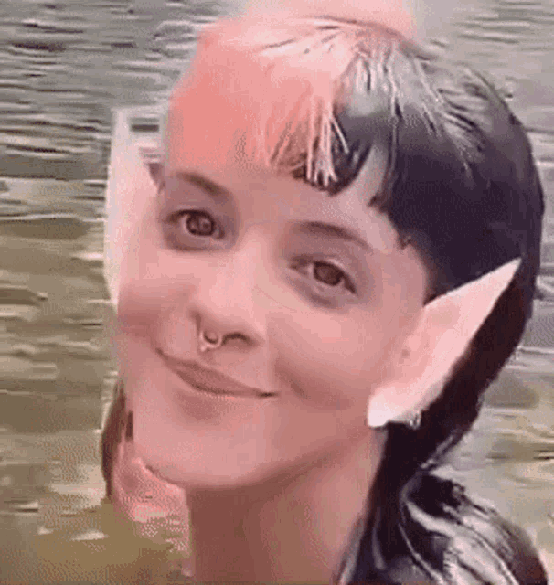 a woman with pink hair and elf ears is swimming in the water .