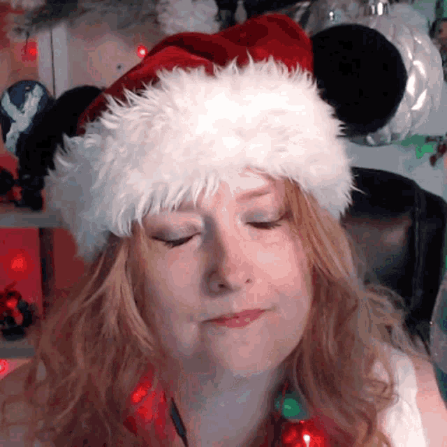a woman is wearing a santa hat and making a funny face