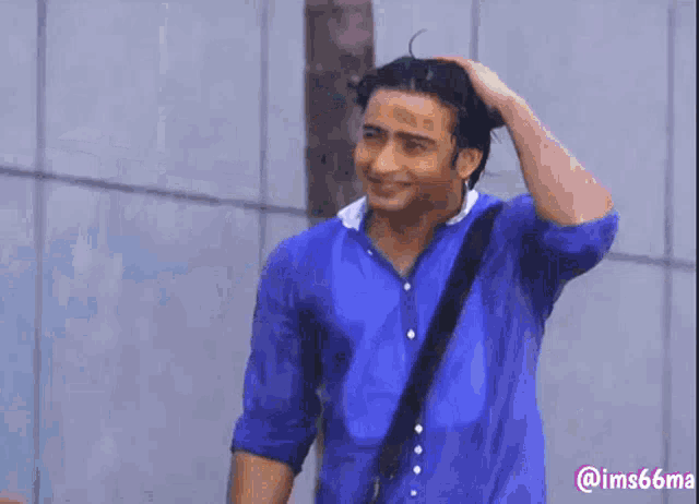 a man in a blue shirt is smiling and holding his head .