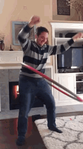 a man in a striped sweater is playing with a hula hoop
