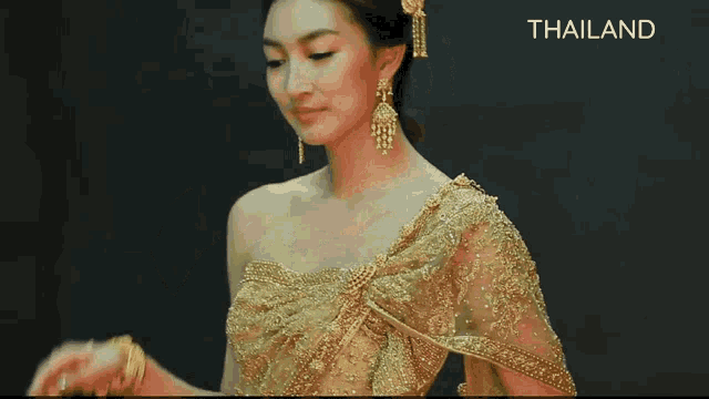 a woman is wearing a gold dress and earrings and is dancing .