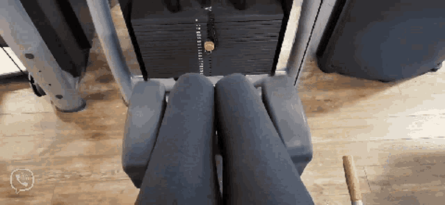 a person is doing leg exercises on a machine with a stack of weights in the background