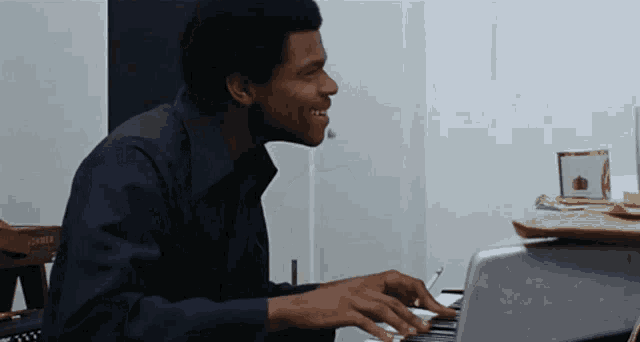 a man in a blue shirt is playing a piano in front of a corner box that says hohner