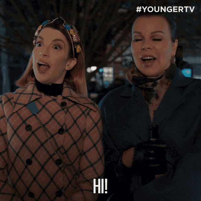 two women standing next to each other and one of them is saying hi