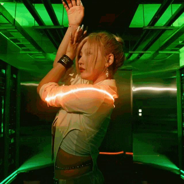 a woman is dancing in a dark room with a green light behind her