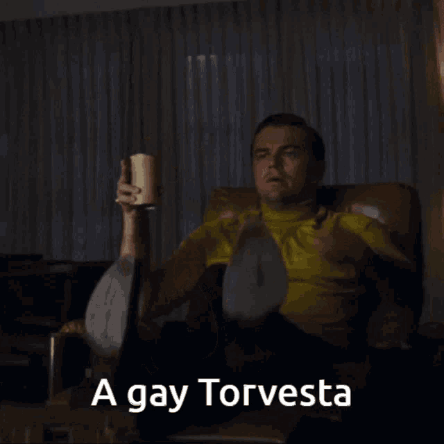 a man is sitting in a chair and pointing with the words a gay torvesta behind him