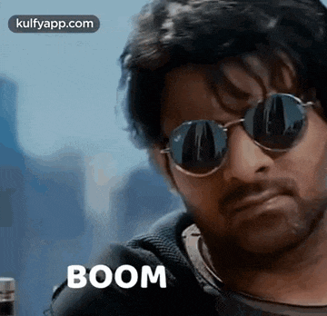 a man wearing sunglasses and a beard is looking at the camera with the word boom written on the bottom .