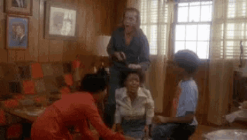 a group of people are standing around a woman sitting on a couch in a living room .