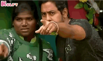 a man and a woman are standing next to each other and the man is pointing at the camera .