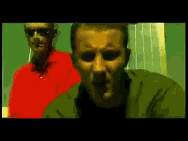 two men are standing next to each other in a dark room .