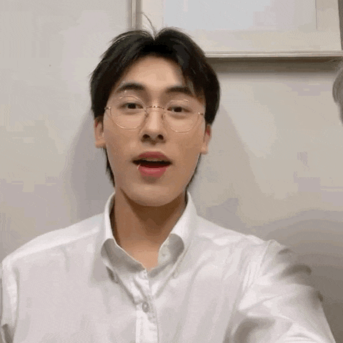 a young man wearing glasses and a white shirt is taking a picture of himself .