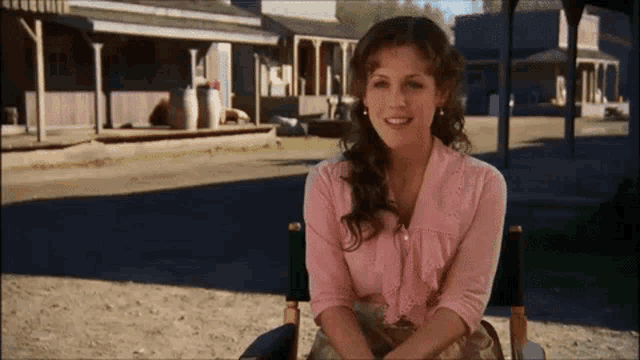 a woman in a pink shirt sits in a chair