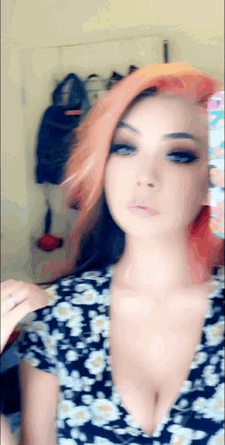 a woman with red hair and a plunging neckline is taking a selfie