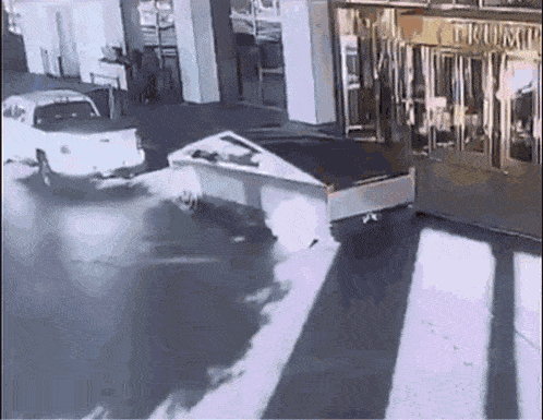 a white truck is driving down a street next to a building with the word trump on it
