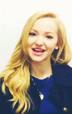 a blonde woman wearing a blue shirt and a black jacket is smiling