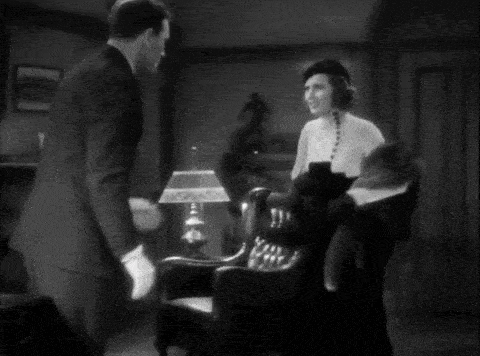 a black and white photo of a woman wearing a hat and fur gloves .