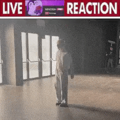a person is standing in an empty room with a live reaction sign above them .