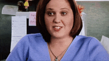 a woman in a blue shirt is sitting in front of a sticky note that says mail a joe