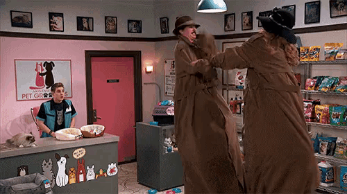 a man in a trench coat is standing next to a woman in a hat in a pet store .