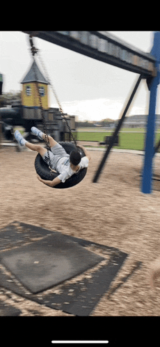 a person is sitting on a tire swing at a playground