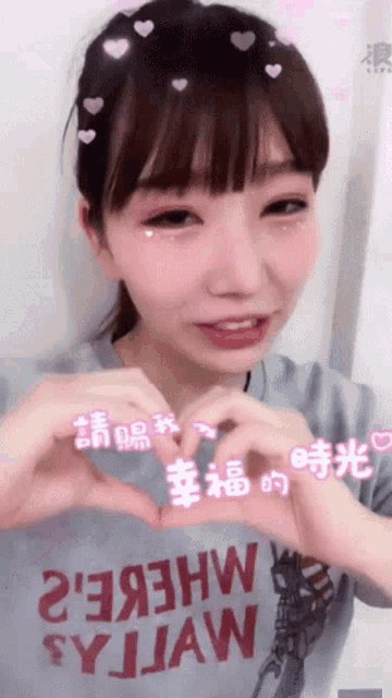 a girl wearing a shirt that says sy jaw making a heart shape with her hands