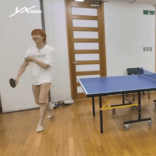 a man is playing ping pong in a room with a sign that says x labels