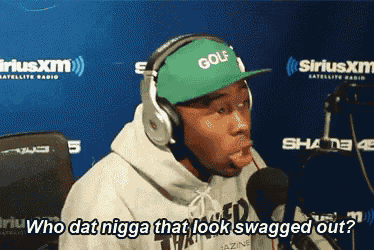 a man wearing headphones and a green hat says " who dat nigga that look swagged out ? "