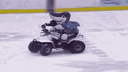 a shark mascot is riding a four wheeler on ice