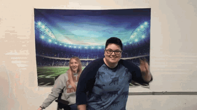 a man and a woman are posing for a picture in front of a stadium tapestry