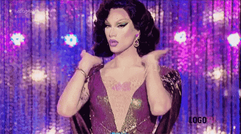 a drag queen in a purple dress is standing on a stage with her arms outstretched .