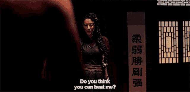 a woman stands in front of a sign that says " do you think you can beat me "