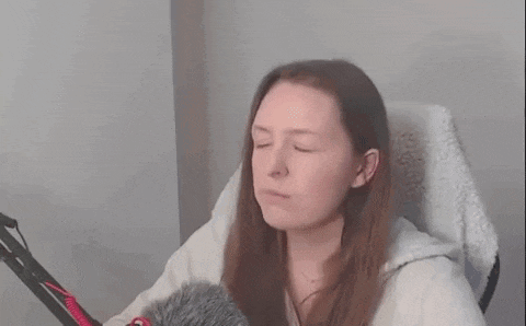 a woman is sitting in a chair in front of a microphone and making a funny face .