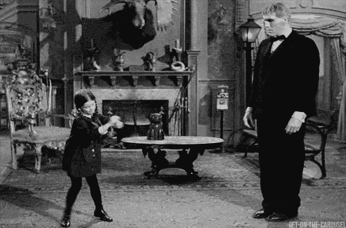 a man in a tuxedo is standing next to a girl in a living room .