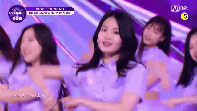 a group of girls are dancing on a stage and one of them is wearing a purple shirt .