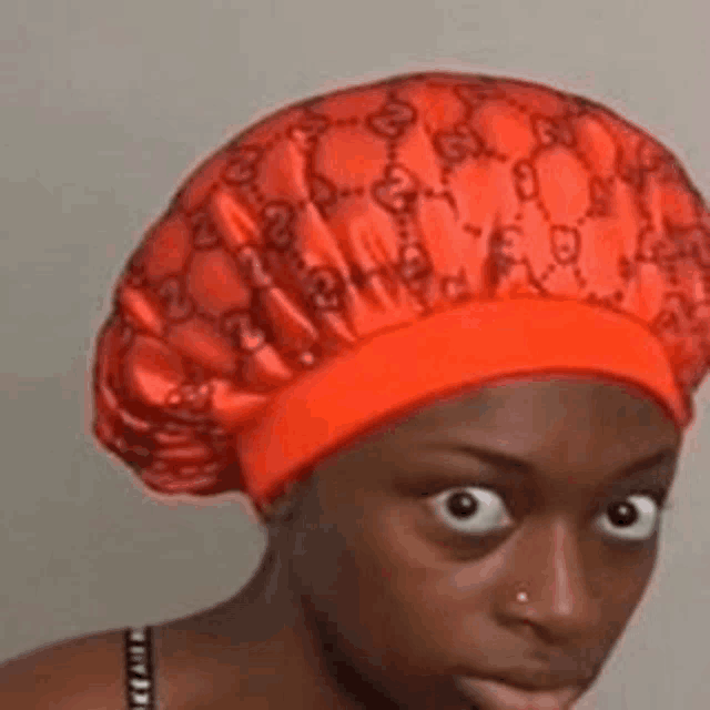 a woman is wearing a red gucci hat and making a funny face .