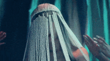 a woman is wearing a veil of pearls and rhinestones